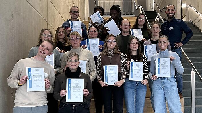 Seminar Teilnehmer mit Dozent stehen auf der Treppe mit ihren Zertifikaten